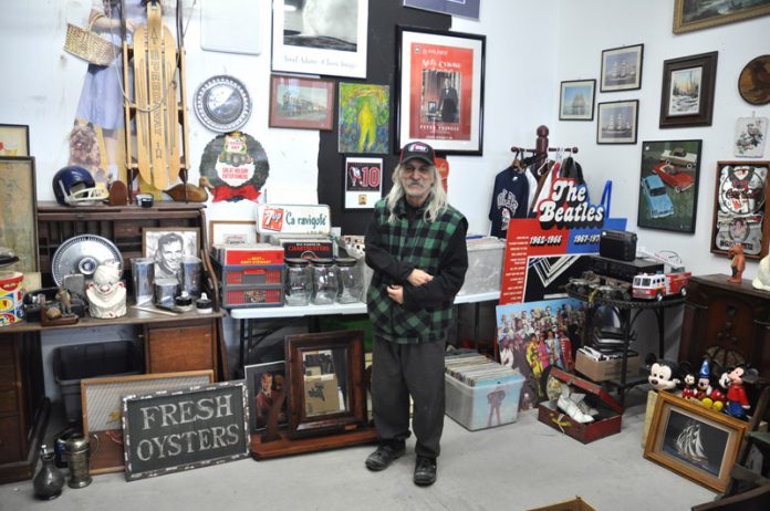 Carl Spano stands in the middle of his antiques store