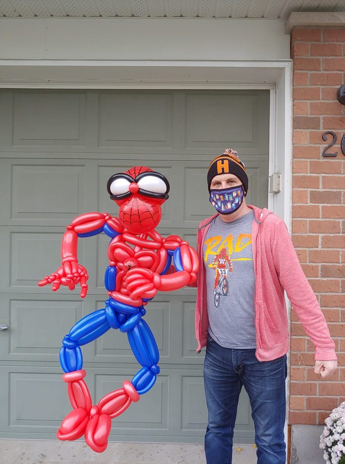 A photo of Brad the Balloon Guy holding a balloon artwork of Spiderman.||