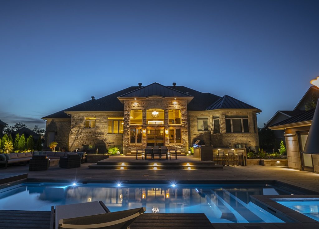 A big, fancy stone house with a large pool in the front. 