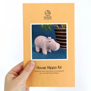 A house hippo sewing kit is being held up in someone's left hand.