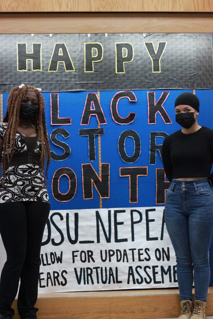 Two students stand in front of a Black History Month display at Nepean High School. The students stand on either side and are wearing masks.