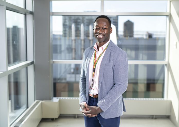 A man stands in a building with windows behind him in a professional photo|