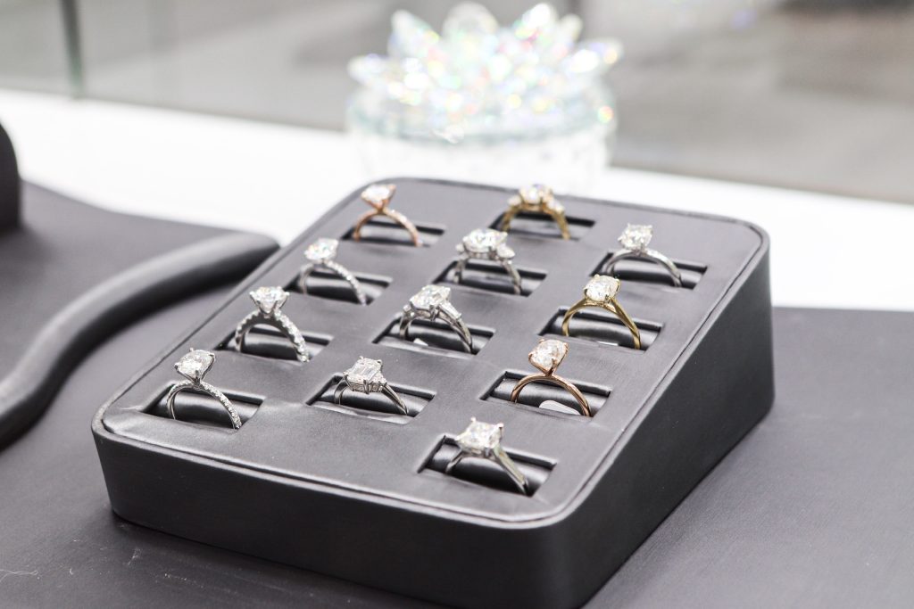 A black tray of moissanite rings is seen on a black countertop.