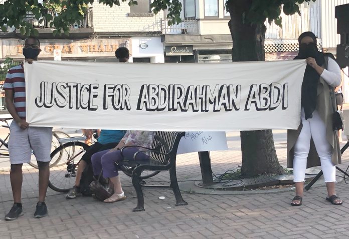 Two organizers holding a banner at 55 Hilda St. on the fourth anniversary of Abdi's death in July 2020.