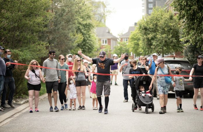 Michael Baine is seen with his family crossing the red ribbon finish line for his half-marathon walk in Westboro