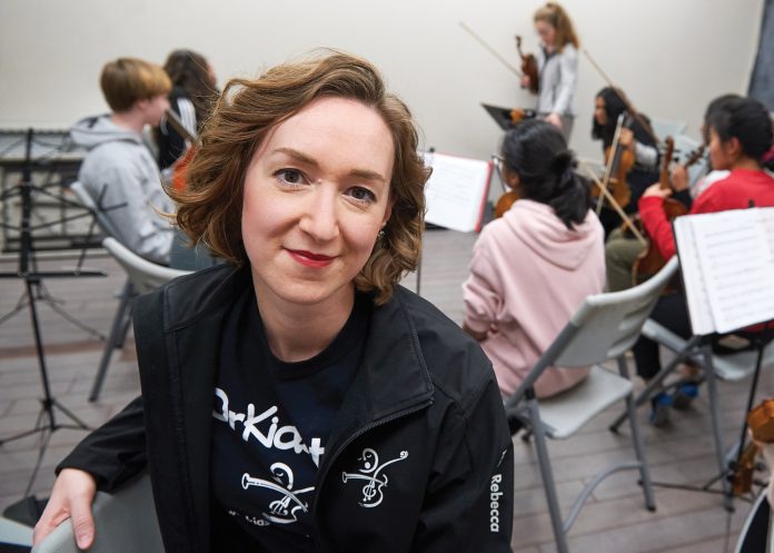 Kitchissippi resident Rebecca Russell poses in front of youth playing music