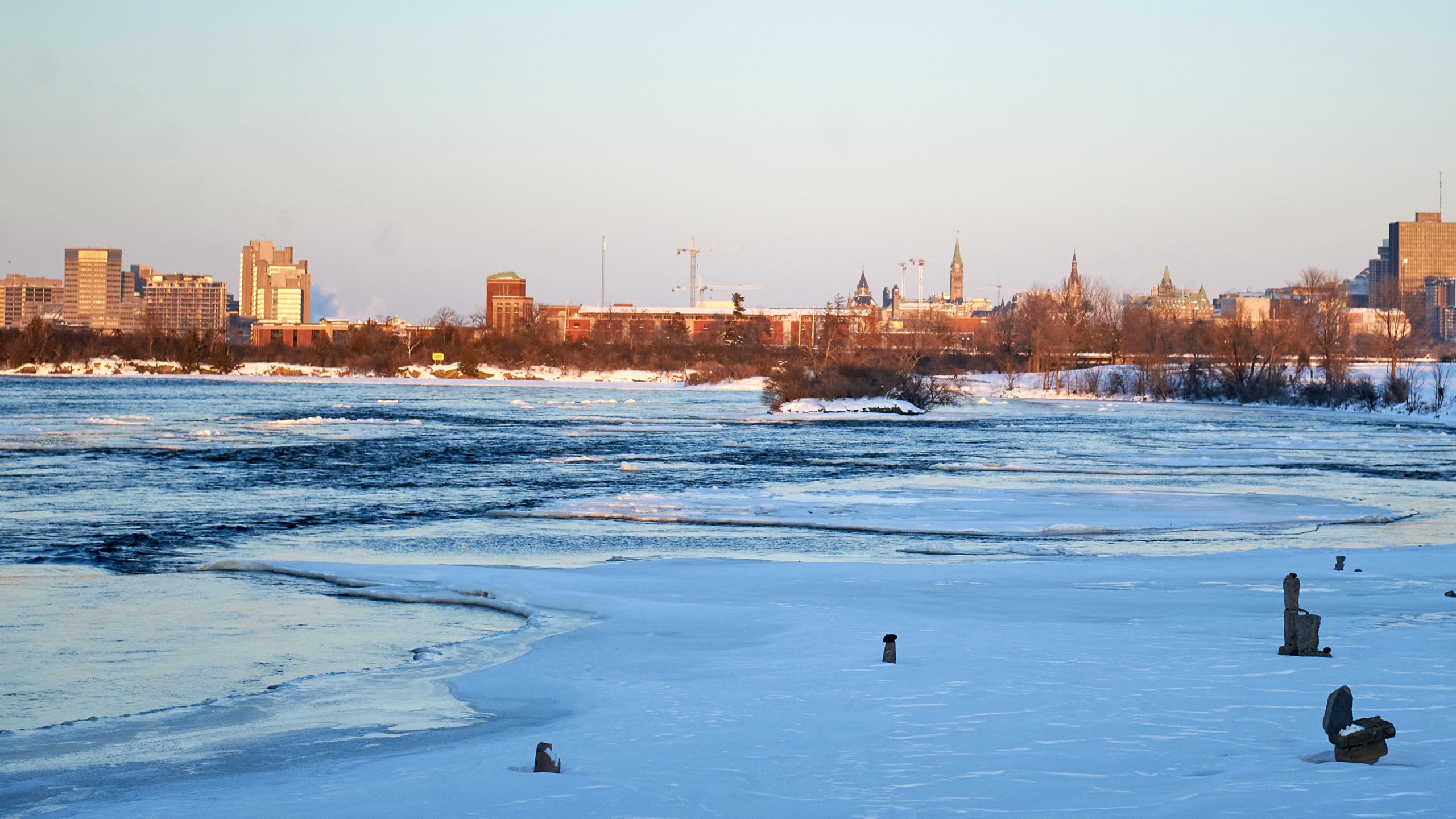 Parliament is seen across a snow covered Ottawa River at sunset.