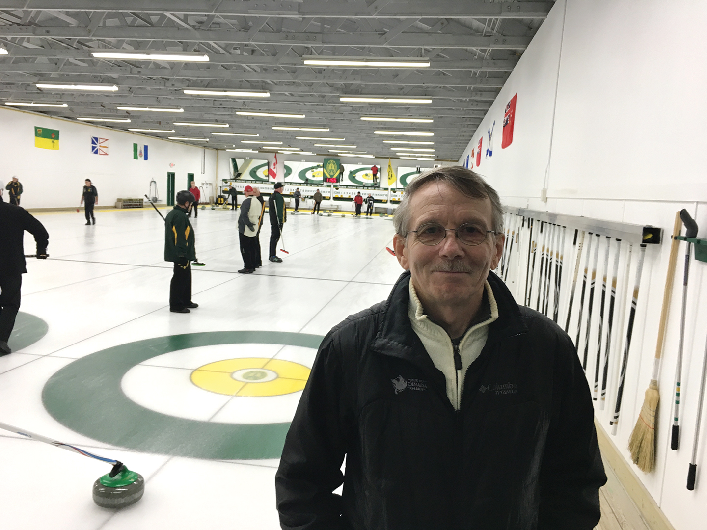 Greg Mathieu, Chair of the Granite Club’s redevelopment committee, stands in front of a curling rink full of curlers. 