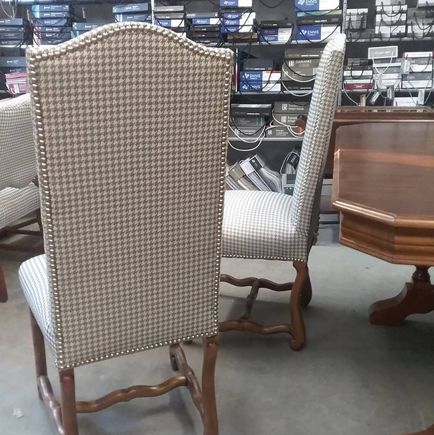 A white and black pattern chair sits in front of two others like it in a furniture store|