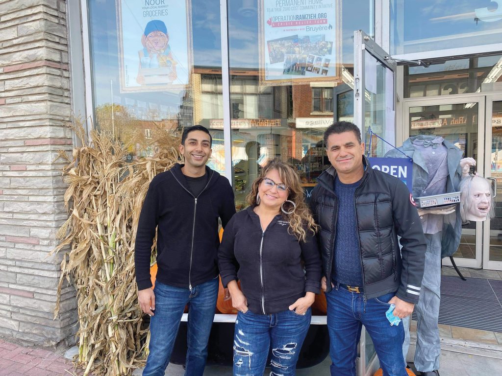 A photo of the three managers and owners of Noor Food Market outside their store in fall.