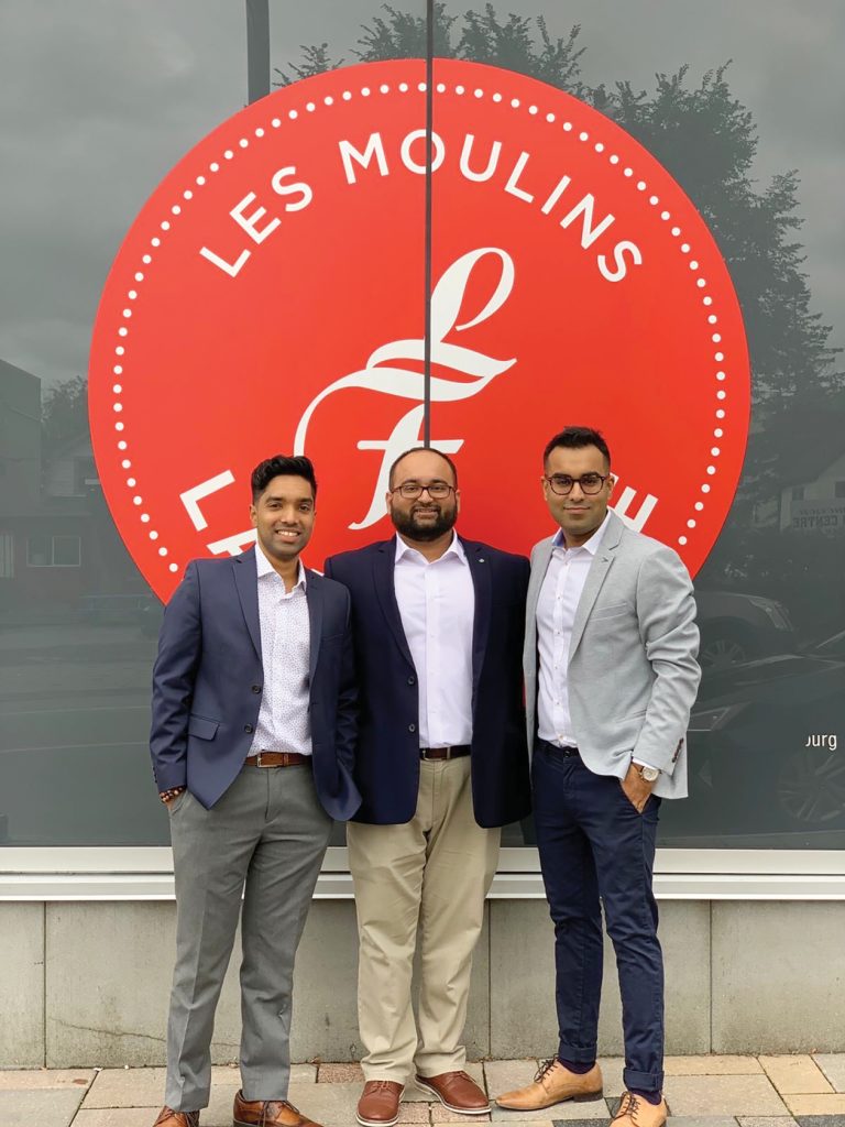 The three co-owners of Les Moulins La Fayette against the company logo in Hintonburg.