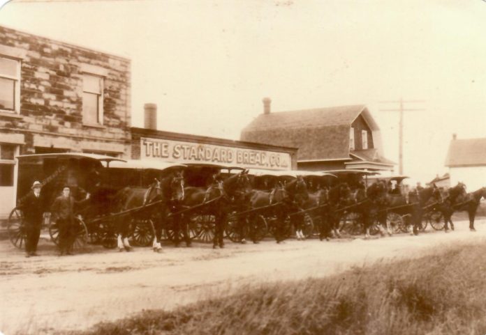 A black and white photo from 1920 outside of a building with the name 