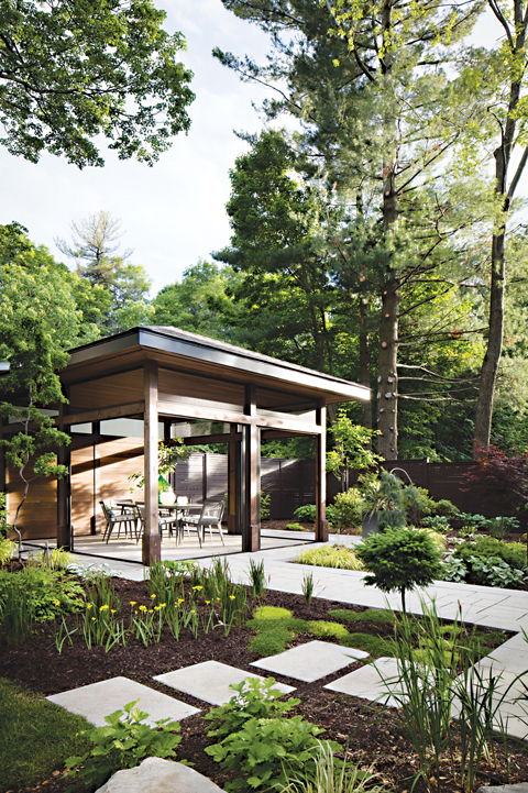 A gazebo is seen in a backyard surrounded by trees and plants in a lawn