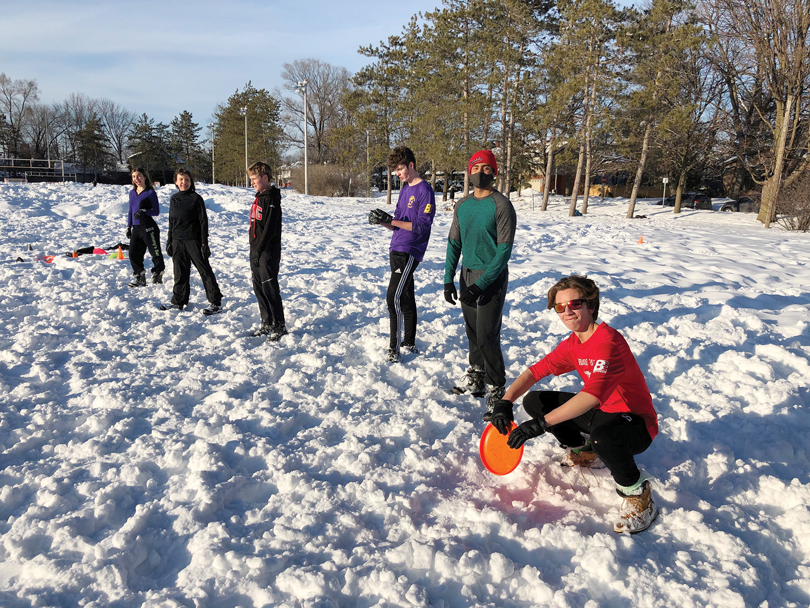 A line up of frisbee players is seen at McKellar Park on a snowy day.