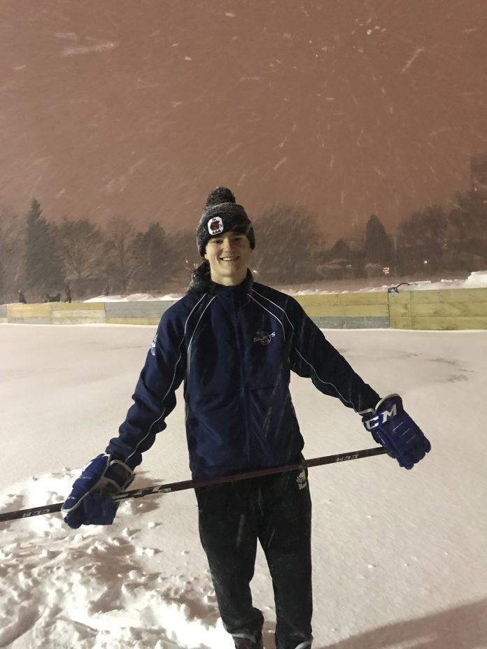 Owen Hollingsworth stands on a snow covered rink during a snowy evening in Ottawa and he holds a hockey stick