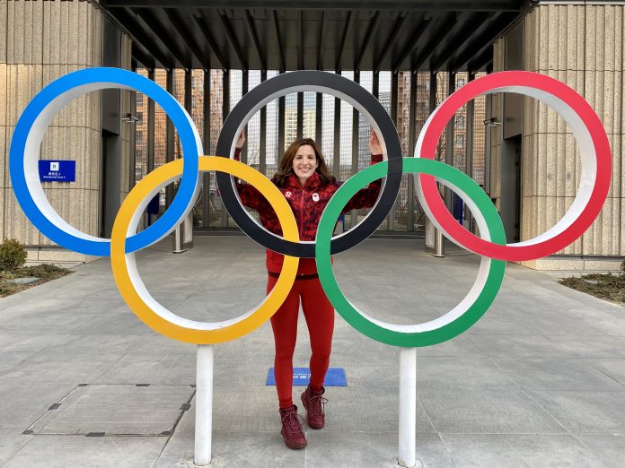 A woman wearing a red athletic suit stands in between Olympic rings outside.|A professional headshot of Lisa Weagle outside of Ottawa city hall.