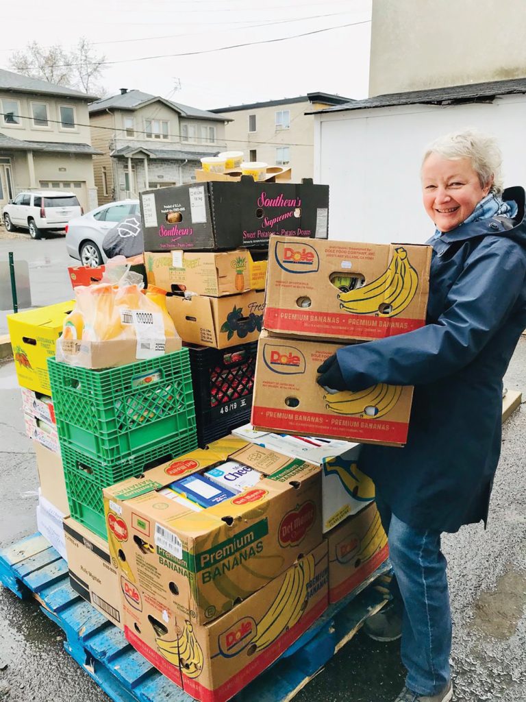 A photo of a volunteer at the Westboro Region Food Bank carrying boxes of food.