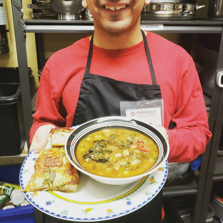 A volunteer holds a soup bowl and plate with bread on it at the Parkdale Food Centre