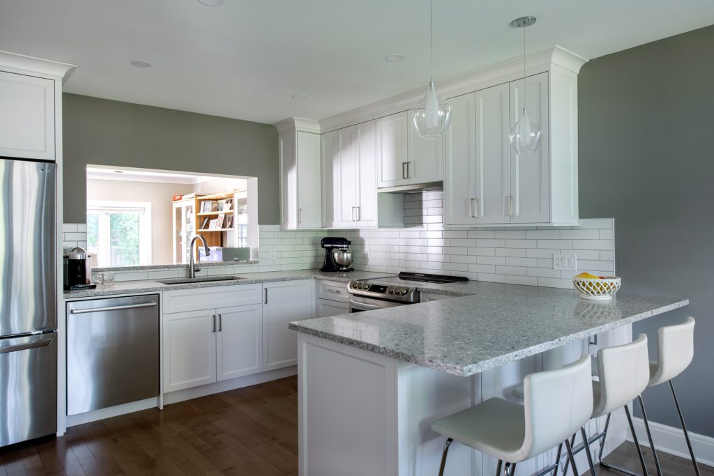 A renovated kitchen in a Westboro home is seen. It has a dark wood floor and white kitchen cabinets and chairs.