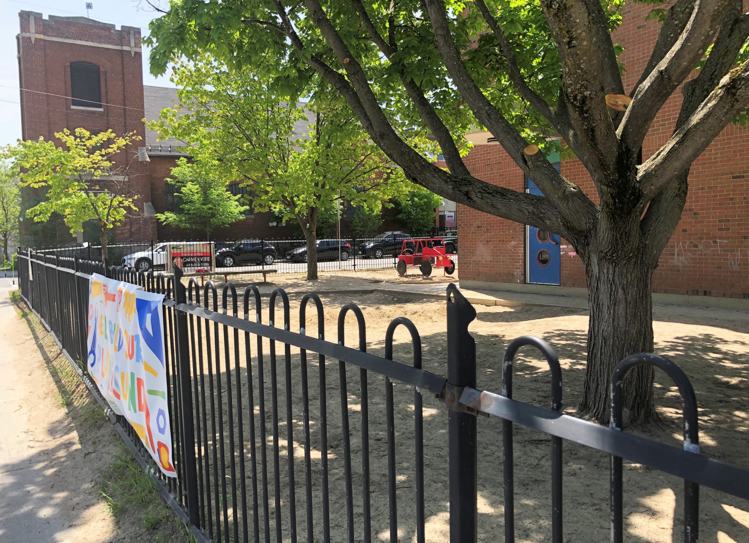 The outside yard for school children at the Churchill Alternative School with the sandy yard and tall tree.