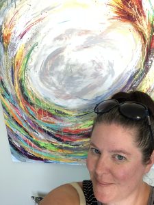 A headshot of Pamela Stewart in front of a multicoloured circle on a painting