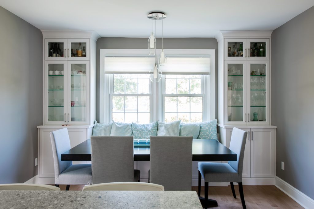 A renovated dining room is seen with white cabinets and a black table with white chairs