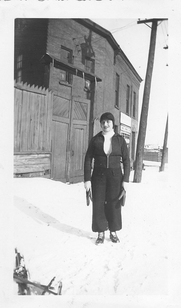 A black and white photo of Fae Taller standing on a snowy Bayview Road in the 1930s in Hintonburg.