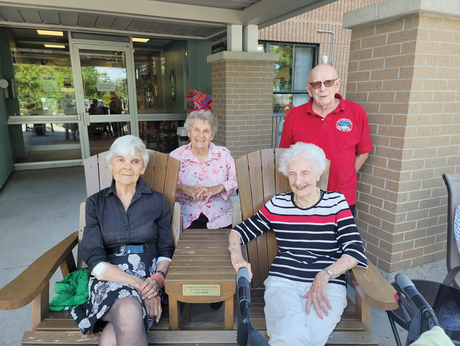 A group of seniors sit outside of Unitarian House on a sunny day in Ottawa