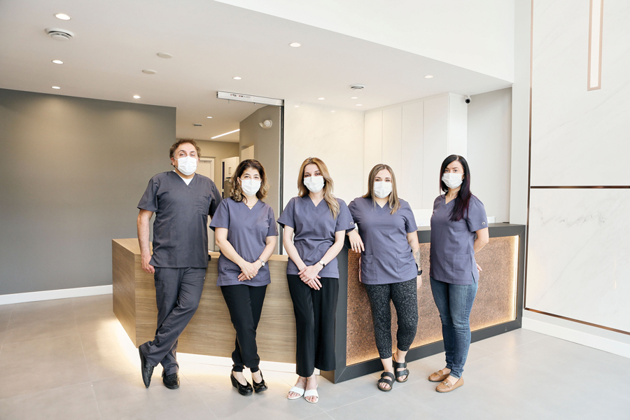 The team at W Dental Studio is seen wearing scrubs and masks standing in a line in the main lobby