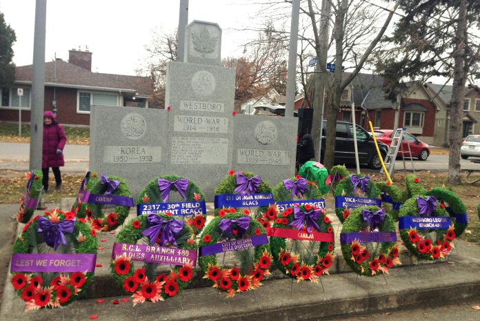 Remembrance Day wreaths are seen lined up at a cenotaph|