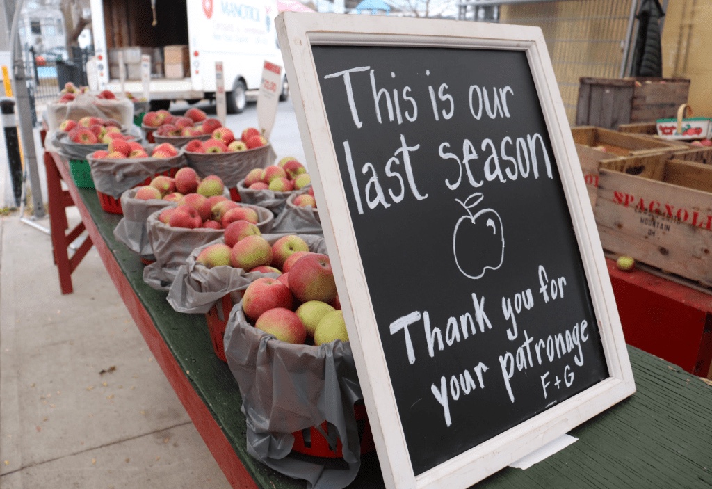 A sign written on a chalk board let’s people know this is the apple stands last season in business. 