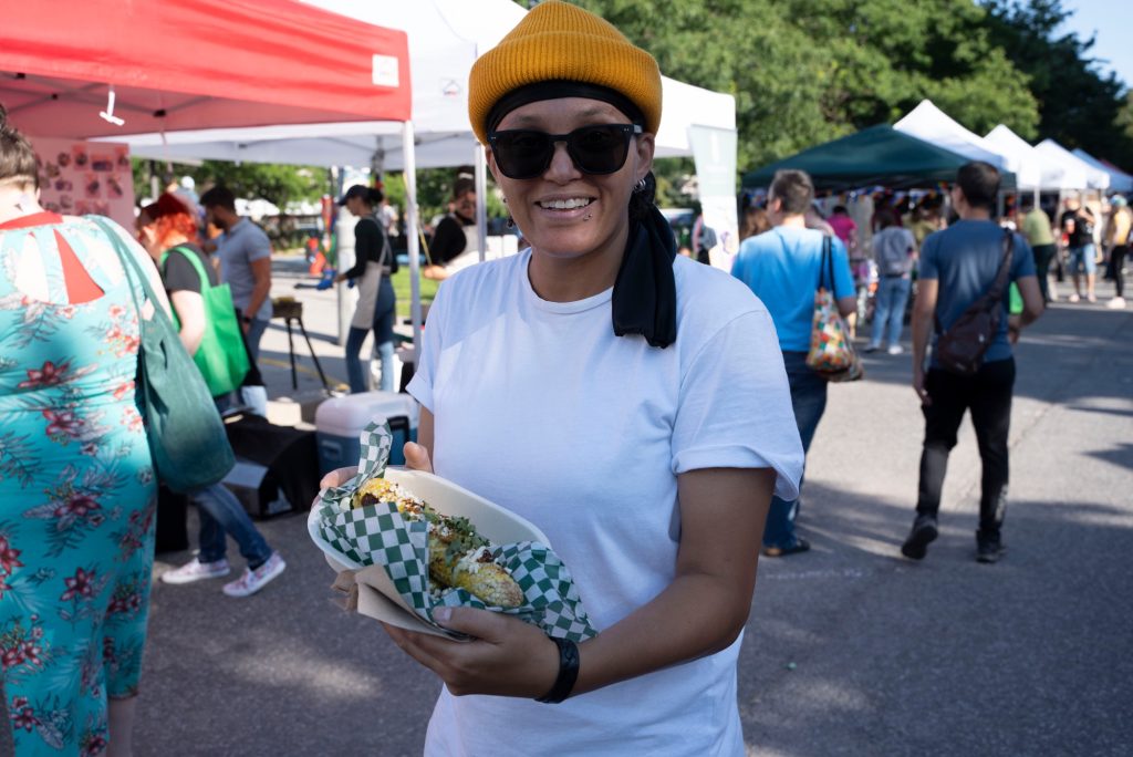 A person at the market holds up their food. 