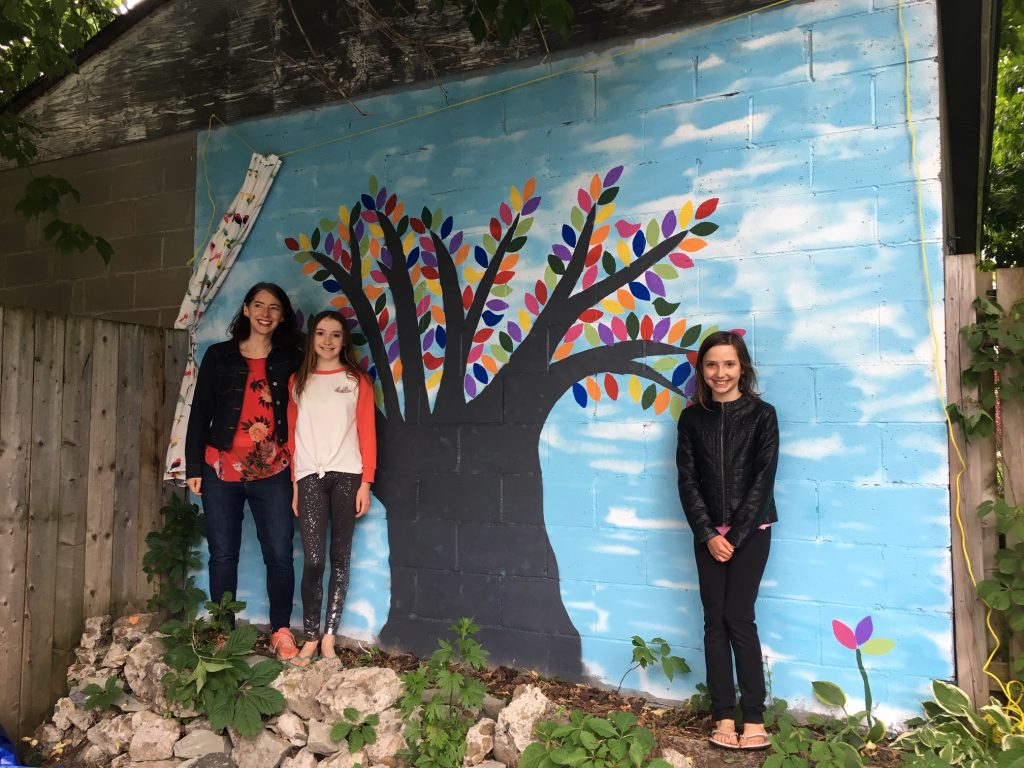 A photo of the Thomson family and their painted tree mural in Hintonburg.