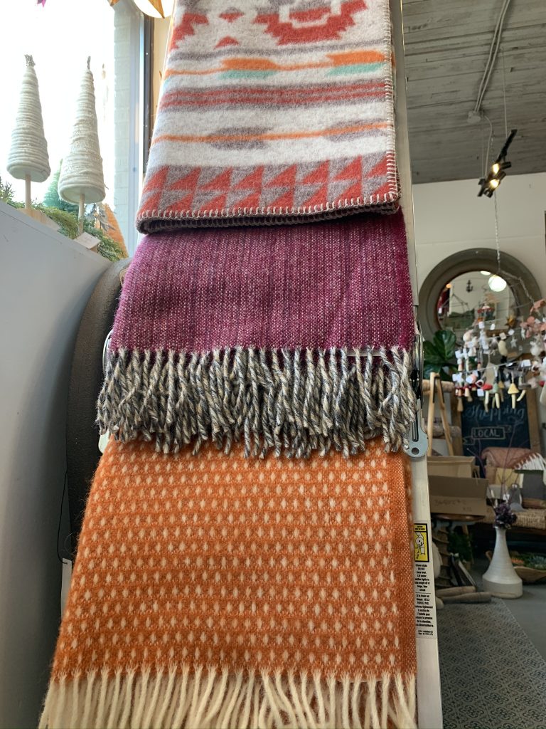 Three multicoloured wool blankets are folded over a ladder