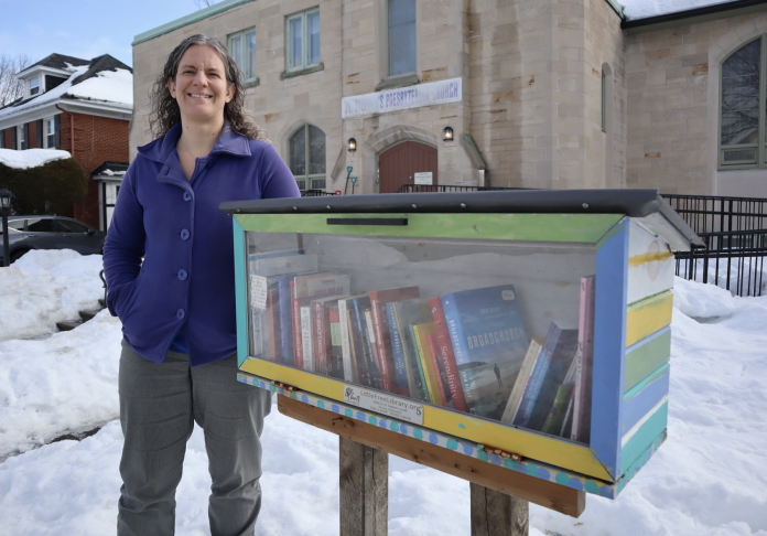 Meg Paterson stands beside a colourful library box outside of St. Stephens Presbyterian Church