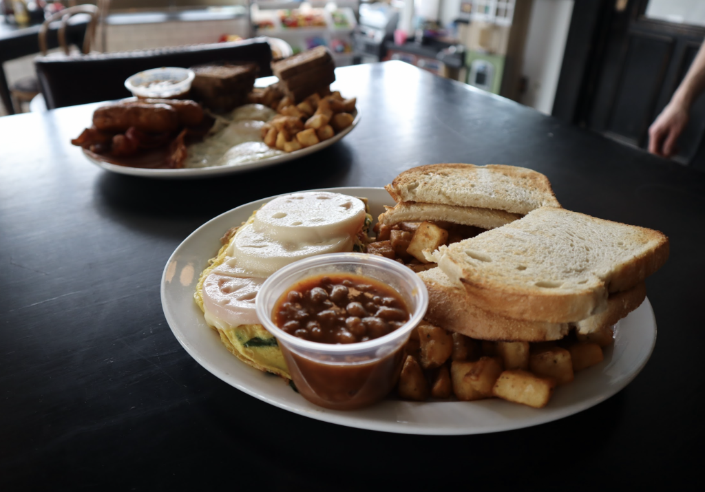 Bacon, eggs, assuage, toast, home fries, and other food sits on two plates.