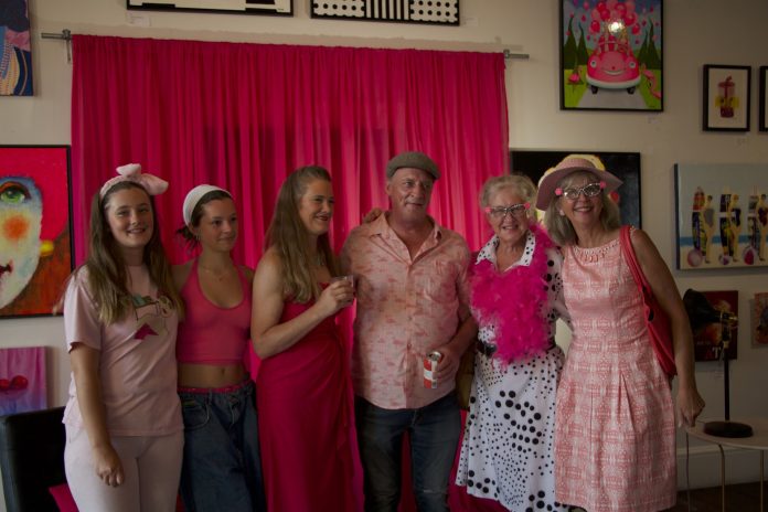 Six people wearing pink pose for a photograph.