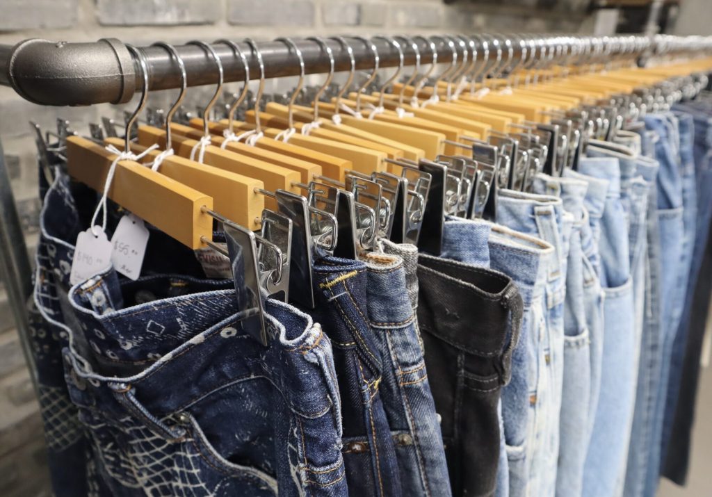 Many pairs of blue jeans in different shades sit on a rack. 