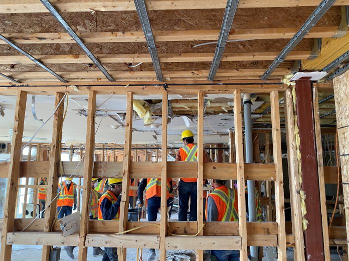 Construction crews work to remove the walls inside Ottawa Salus. All that’s left is the wooden beams.