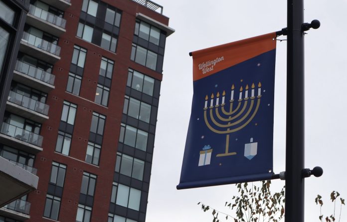 A flag banner on a light post with a giant menorah on it