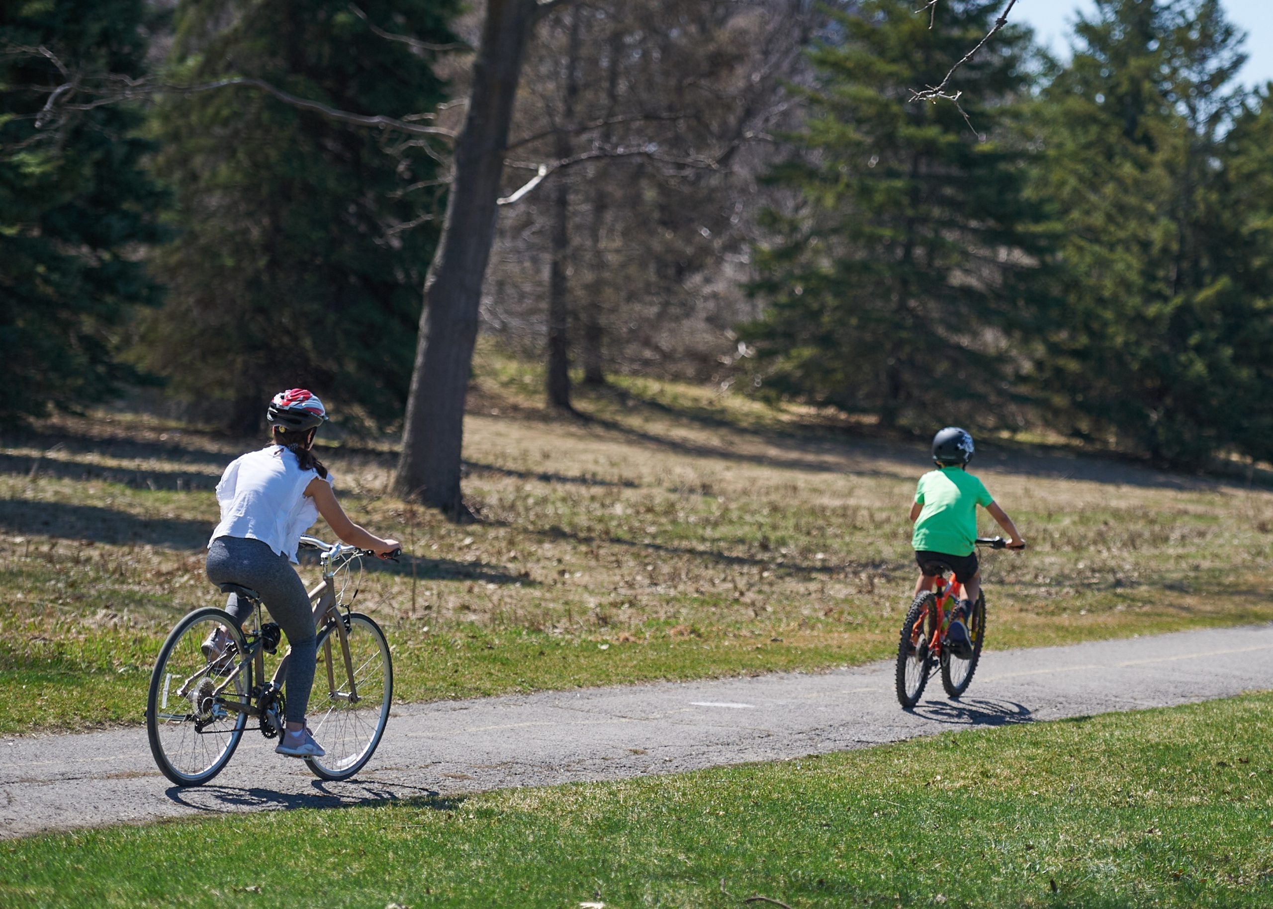 A woman and a young boy out for a bike ride on a bike path. It’s a sunny day. 