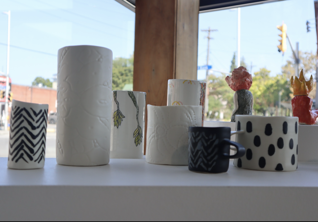 Multiple vases sit in the art galleries front window. 