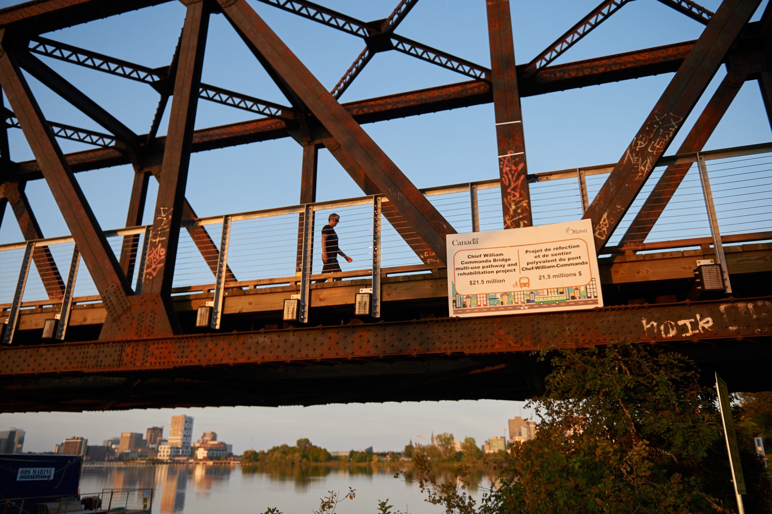 A person is seen walking on the bridge. The photo is taken from the path below. 