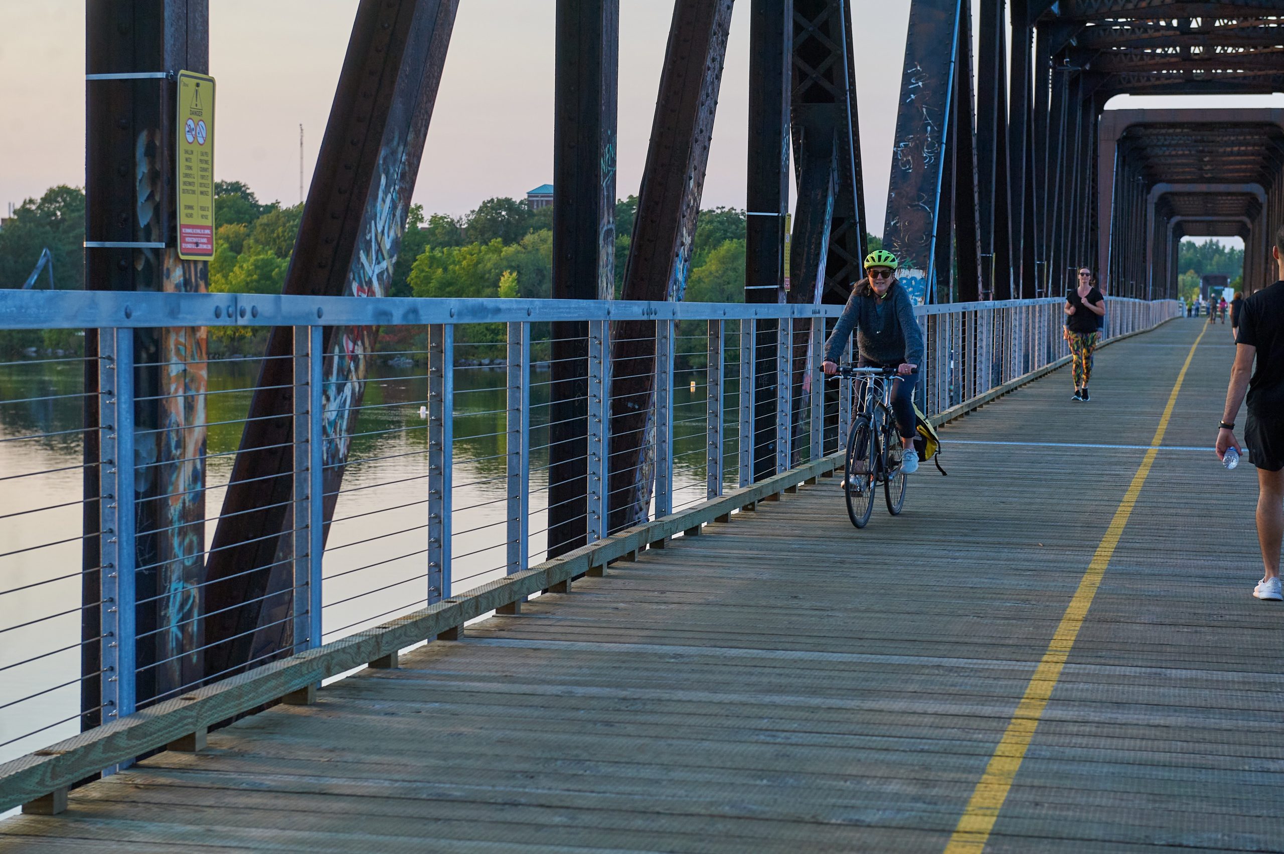 Beth crosses the bridge on a bike. 