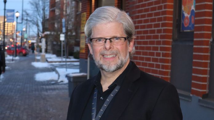 Dennis poses for a photograph outside the Wellington West BIA office. It’s winter and the sun is setting.