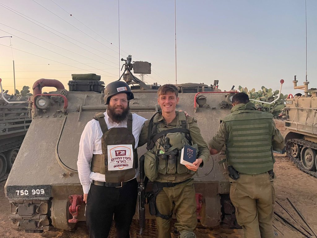 Moshe Caytak poses for a photo with a member of Israelis military unit and a large tank. 