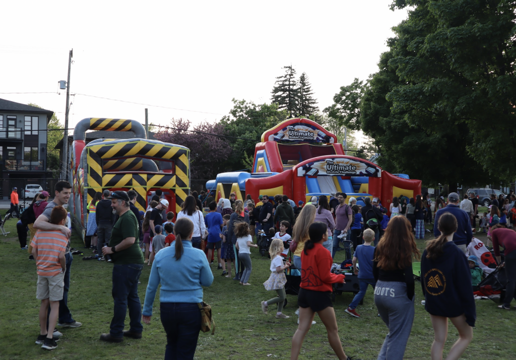 Many people stand around two bouncy castles.