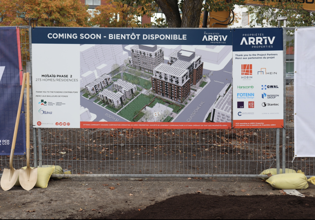 Drawings for the new affordable housing complex are displayed on a poster attached to a fence. 