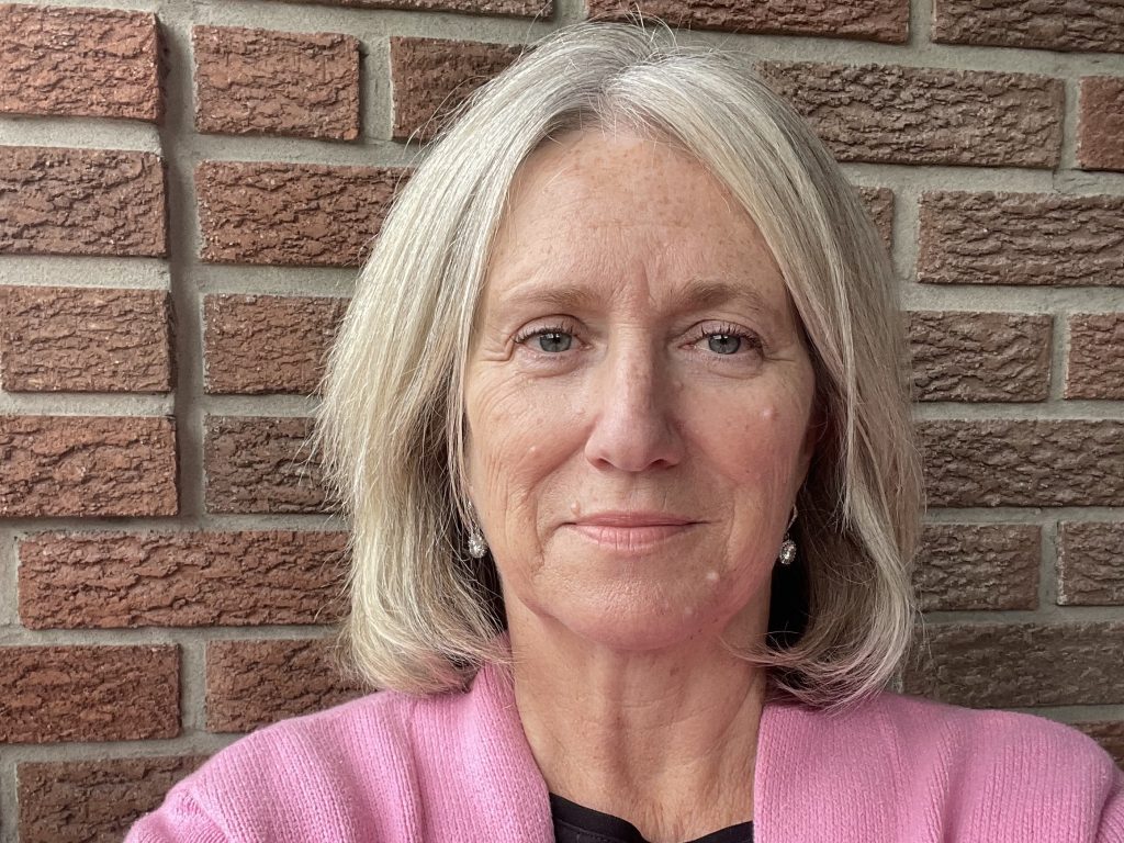 Donna poses for a selfie next to a brick wall. 