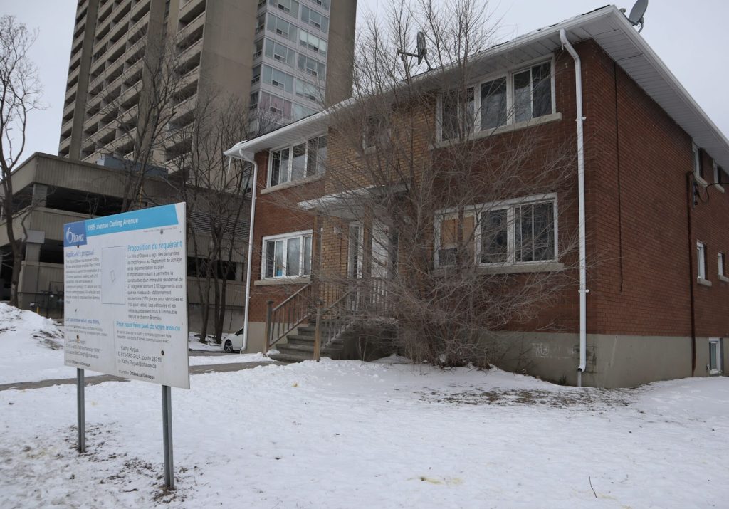 A planning sign sits outside of a small two-storey housing complex. 